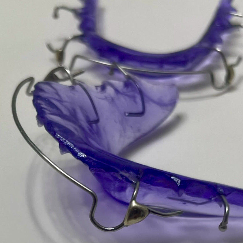 Two purple dental retainers on a white background